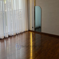 A bright room in Lahore featuring highly reflective, high-gloss Chaina Floor 12 MM rosewood laminate seamlessly installed next to floor-to-ceiling sheer curtains