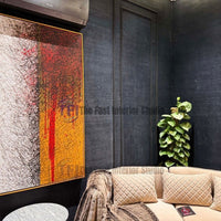 A close-up interior view of a dark navy blue jute wallpaper accent wall styled with a tall green indoor plant and a large framed abstract painting