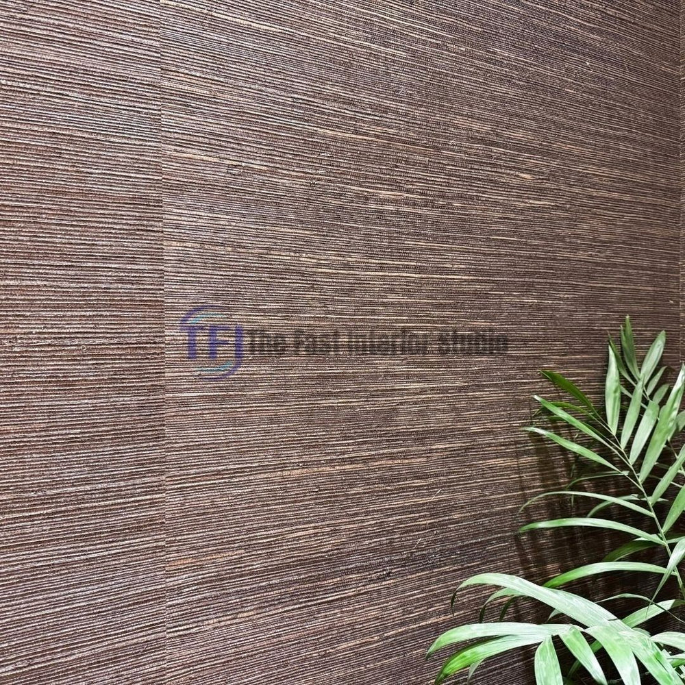 A close-up macro shot showcasing the rich horizontal woven texture and dark brown fibers of a jute wallpaper installation beside a green plant leaf