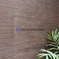 A close-up macro shot showcasing the rich horizontal woven texture and dark brown fibers of a jute wallpaper installation beside a green plant leaf