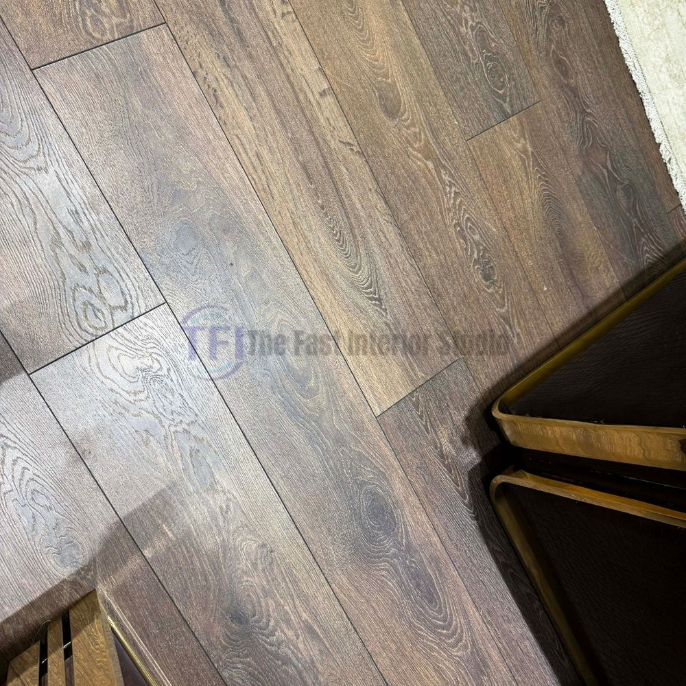 A close-up view of premium AGT wood grain laminate flooring, highlighting its authentic texture, organic tonal variations, and seamless plank joints next to luxury brass-accented furniture