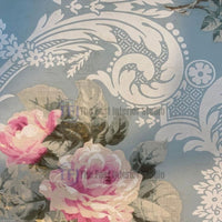 A detailed view of a vintage floral mural wallpaper showcasing vibrant pink roses set against intricate white Victorian damask scrolls on a blue-grey background