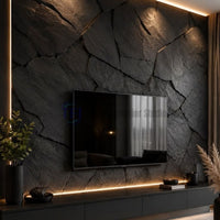 A dramatic dark charcoal 3D PU geometric slate feature wall used as a modern TV backdrop, illuminated by warm ambient LED strip lighting along the edges and above the floating media unit