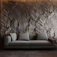 A dramatic modern living room showcasing a dark grey 3D PU cliff rock feature wall with deep diagonal striations installed behind a sleek contemporary grey sofa