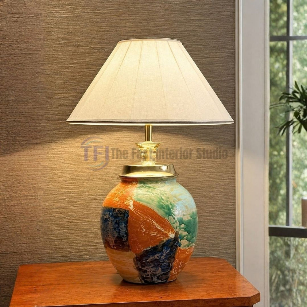A hand-painted abstract ceramic table lamp featuring a pleated cream shade, styled on a wooden surface for luxury interiors