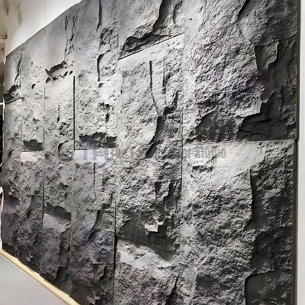 A large feature wall cladded with interlocking dark charcoal 3D PU faux stone panels, showcasing deep, realistic cliff rock textures under accent lighting
