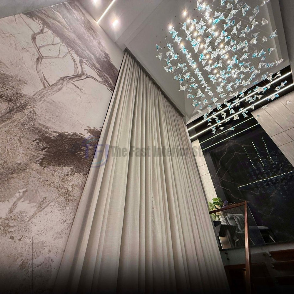 A low-angle architectural view looking up at massive tailored curtains installed next to a detailed wall mural and a stunning cascading glass chandelier