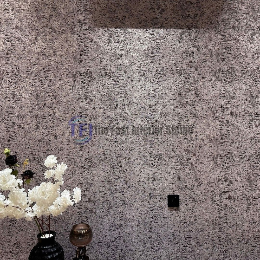 A modern interior wall featuring a heavily textured metallic dark finish, styled alongside a black vase filled with white floral arrangements and ambient lighting