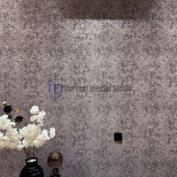 A modern interior wall featuring a heavily textured metallic dark finish, styled alongside a black vase filled with white floral arrangements and ambient lighting
