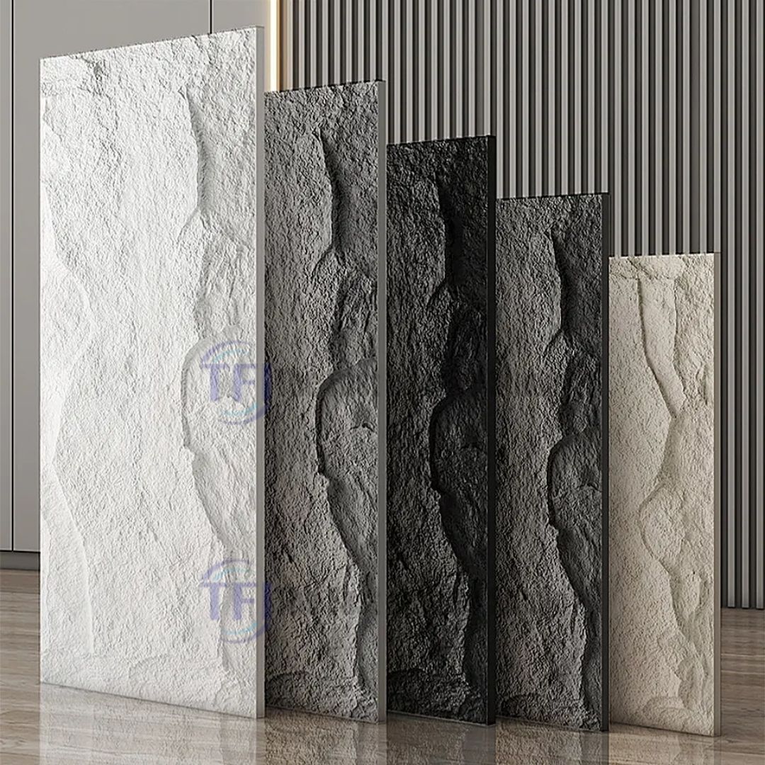 A premium showroom display featuring five vertical 3D PU chiseled rock wall panels arranged in a gradient of colors including white, light grey, dark grey, black, and warm beige