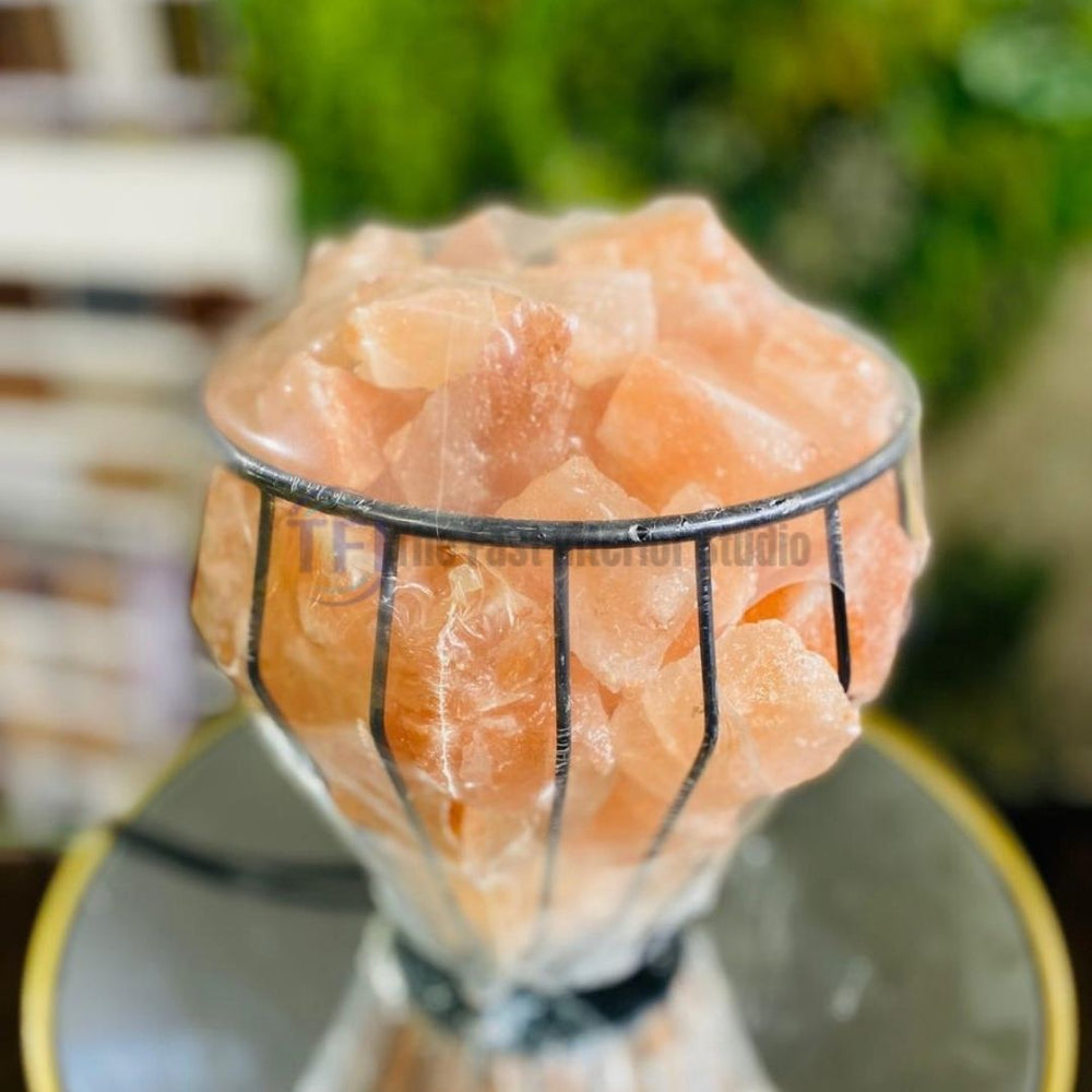 A rustic Himalayan salt lamp featuring raw pink salt chunks beautifully displayed inside a curved, vertical slatted wooden barrel structure