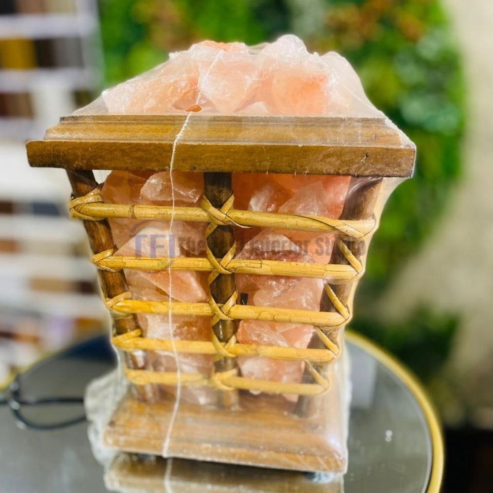 A rustic Himalayan salt lamp featuring salt chunks displayed in a tapered woven rattan basket on a wooden base