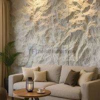 An elegant living room showcasing a highly textured light grey 3D PU chiseled rock feature wall behind a neutral beige sofa