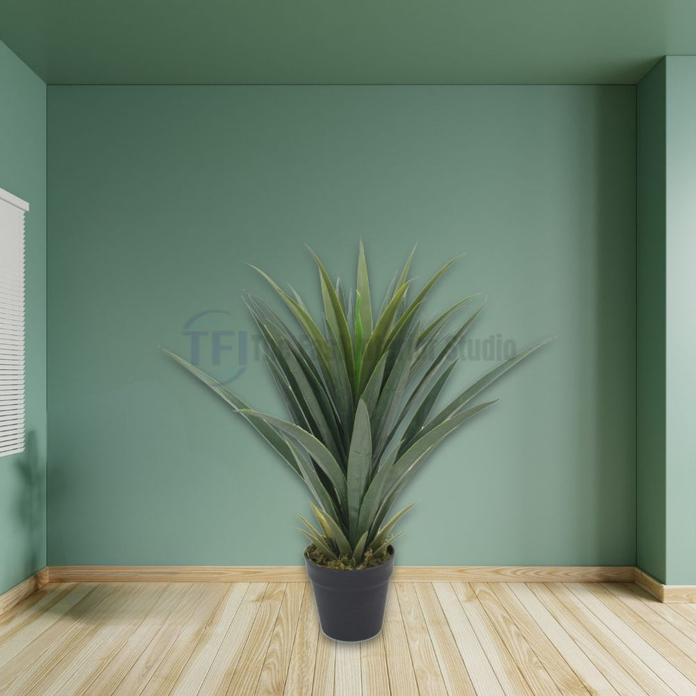 Artificial spiky agave-style plant in a black pot placed in an empty green room