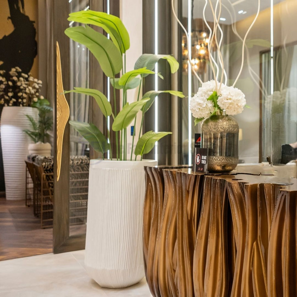 Close-up of a luxury artificial indoor plant in a tall ribbed white planter enhancing a modern dining room