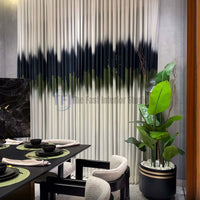 Close-up of pleated white curtains with a dark abstract stripe next to an indoor potted plant