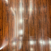 Close-up top-down view of Chaina Floor 12 MM high-gloss laminate planks, showcasing rich reddish-brown wood tones and striking reflective grain patterns
