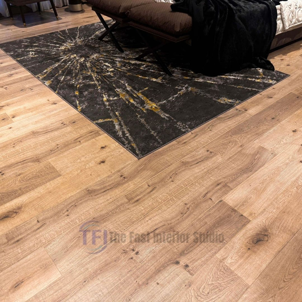 Close-up view of light warm oak laminate flooring with prominent natural wood knots, installed seamlessly next to a dark and gold textured area rug
