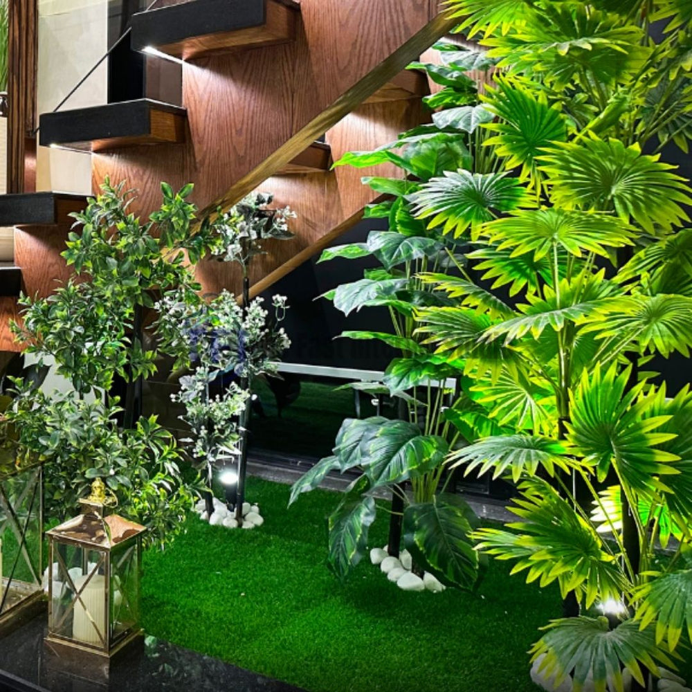 Custom artificial indoor garden installation with faux grass and white stones beneath a modern wooden staircase