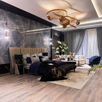 Expansive master bedroom featuring a dark blue velvet bed and dramatic dark marble accent walls, completely grounded by premium AGT taupe wood laminate flooring