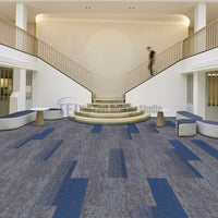 Grey carpet tiles with vibrant blue accent lines installed in a grand modern lobby with stairs in Lahore