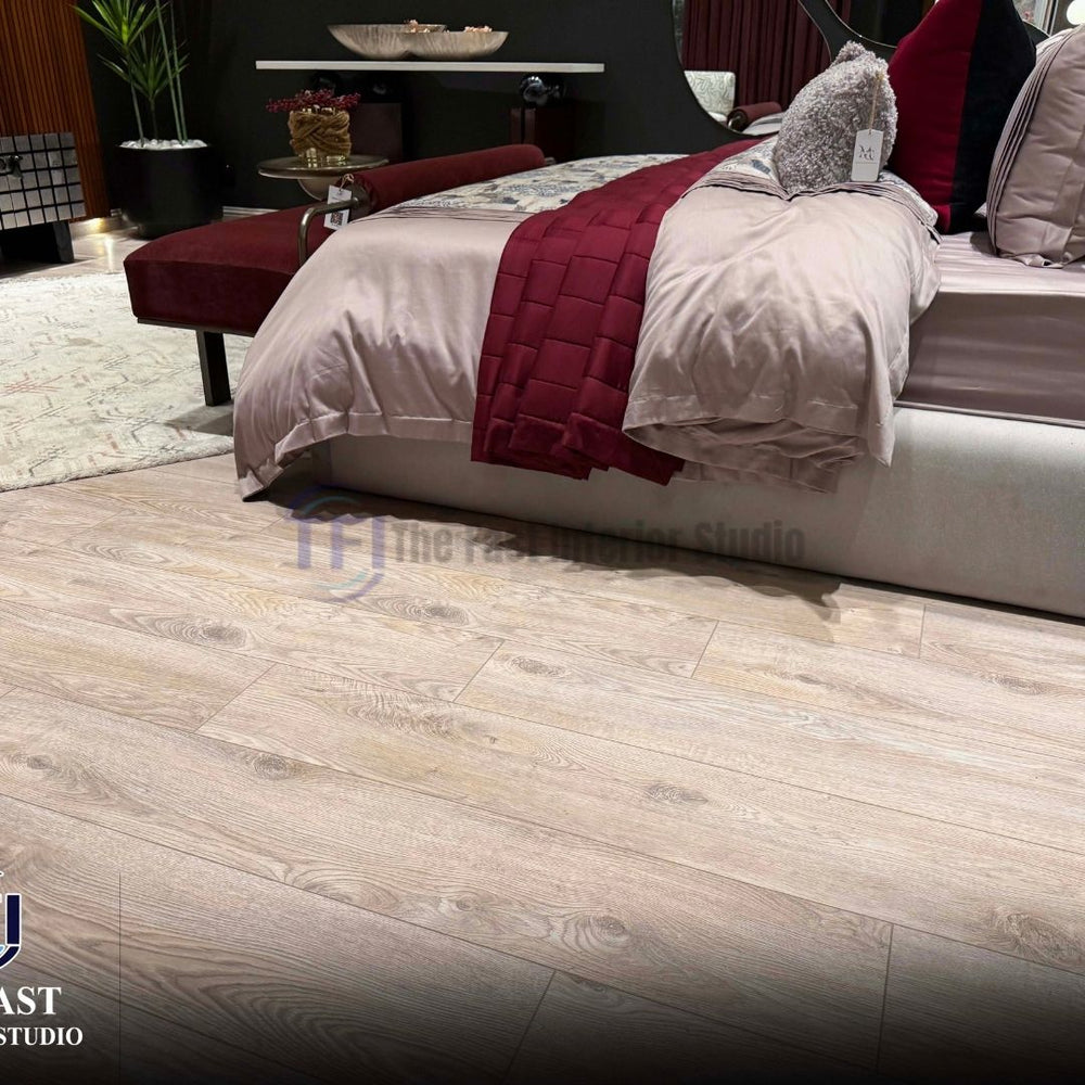 Light pale oak wood laminate flooring installed in a luxury bedroom featuring a deep red bed runner and a matching velvet bench