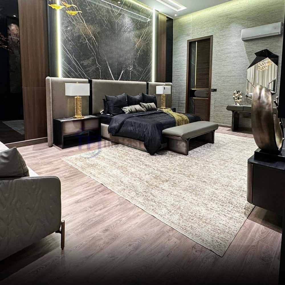 Medium-brown AGT wood laminate flooring installed in a luxury bedroom featuring a dramatic marble accent wall, a dark bed, and a large textured area rug