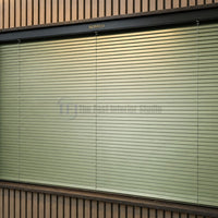Modern sage green Venetian window blinds complementing wooden slat wall paneling