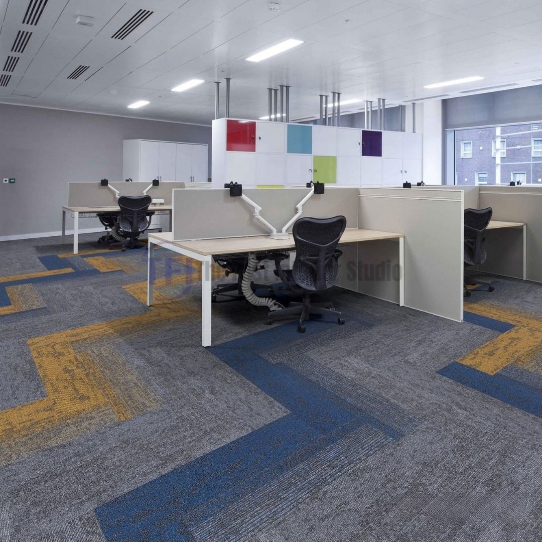 Modular carpet tiles featuring grey and yellow geometric patterns inside a contemporary corporate office workstation