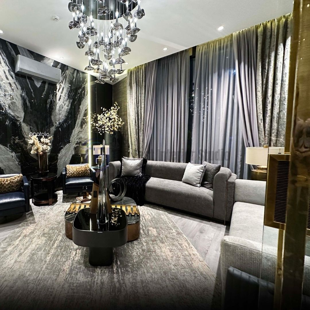 Pleated grey curtains in a modern living room featuring a dark marble accent wall and grey sofas