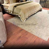 Rich reddish-brown cherry wood style laminate flooring installed in a luxury bedroom setting beneath a striped bedspread, a beige textured rug, and modern seating
