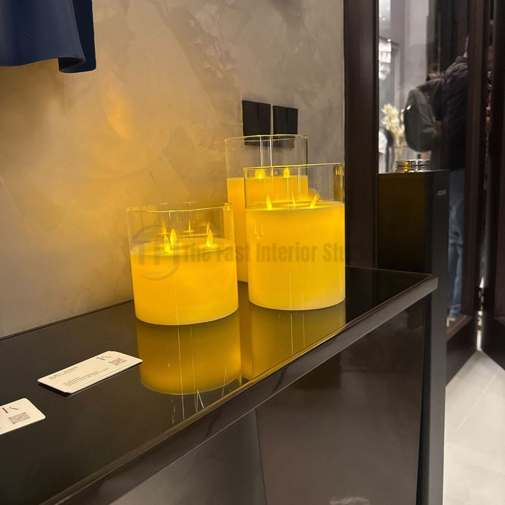 Set of three premium yellow ambient candles in clear glass cylinders displayed on a luxury dark console table, available in Pakistan and worldwide