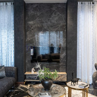 Sheer white curtains beside a dark marble living room media wall