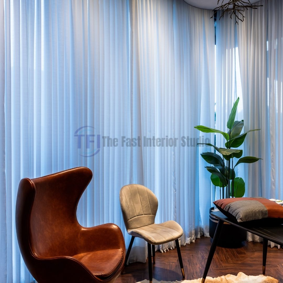 Sheer white floor-to-ceiling curtains behind a modern brown leather armchair