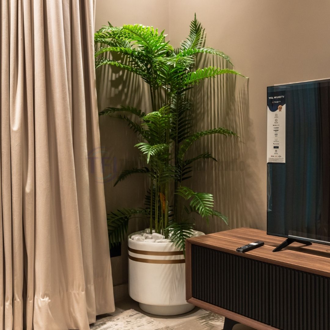 Tall 6-foot artificial palm plant in a white and gold striped pot next to a modern TV console