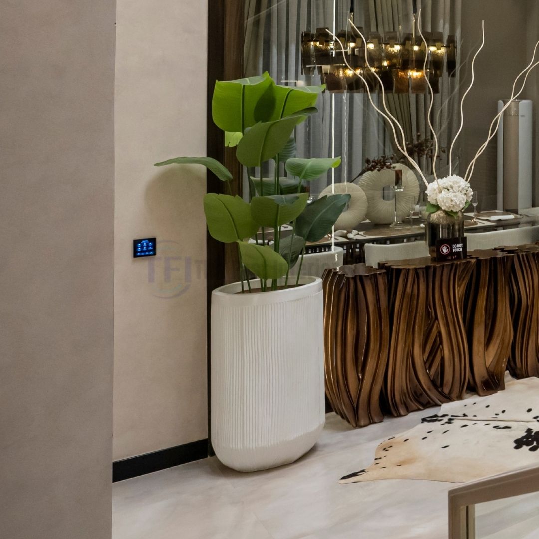 Tall 6-foot artificial plant with broad green leaves in a textured white pot next to a carved wooden console table
