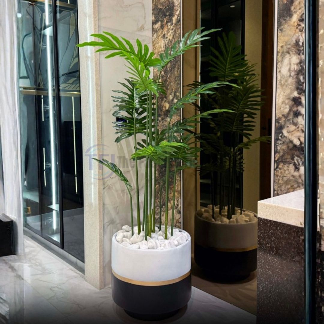 Tall 6-foot artificial plant with split green leaves in a two-tone white and black pot filled with white stones