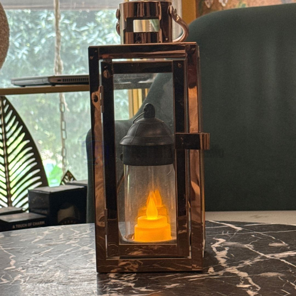 The best modern chrome glass lantern with an LED candle styled on a dark marble table for luxury interiors