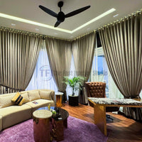 Tied-back taupe drapes and sheer curtains behind a cream sofa and desk