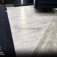 Whitewashed light grey wood laminate flooring providing a bright architectural base next to dark blue velvet furniture and a grey rug