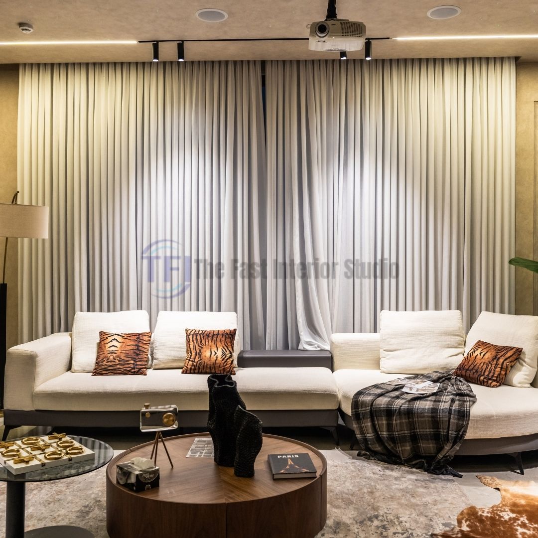 Wide sheer white curtains filtering light behind a modern cream sectional sofa