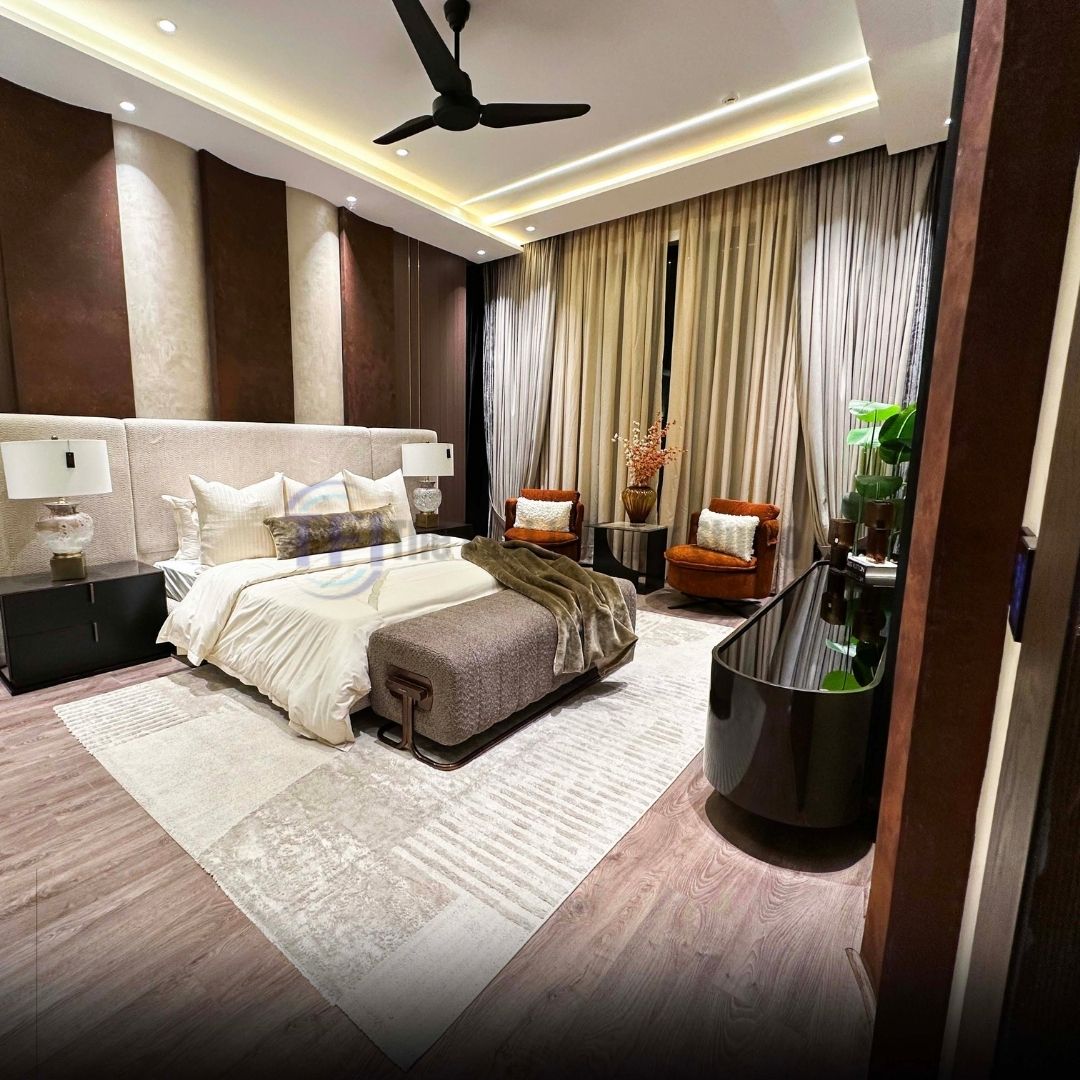 Wide view of pleated beige curtains in a luxury bedroom with rust armchairs